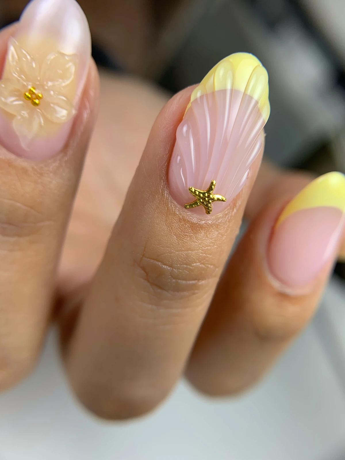 Diseño de uñas en rosa y amarillo con relieves y detalles dorados