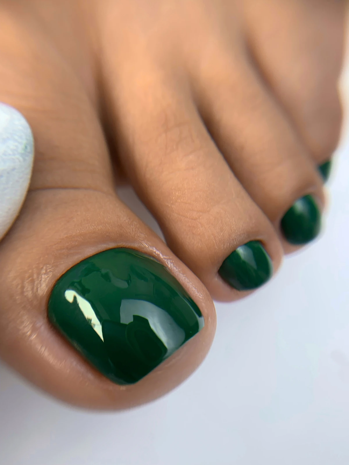 Pedicure con esmaltado verde intenso y acabado brillante